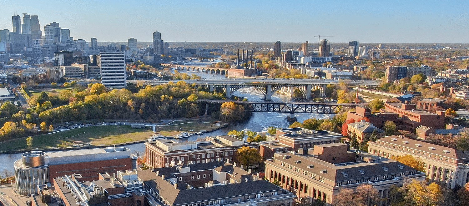 Aerial view of the University of Minnesota East Bank campus, the Mississippi River, and the Minneapolis skyline in autumn